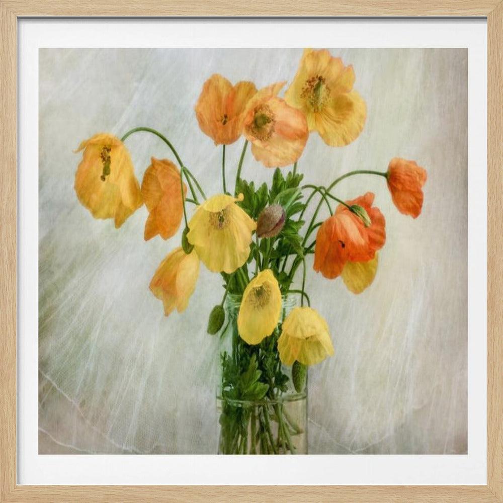 A soft-focus still life photograph of a bouquet of yellow and orange poppies in a clear glass jar, set against a delicate, light green textured background, all enclosed in a light wood frame. Print