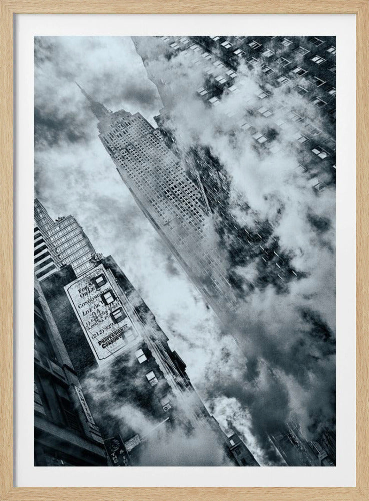 A dramatic, tilted, black and white photograph looking up at a towering skyscraper, likely the Empire State Building, partially shrouded in clouds and steam, creating a moody and atmospheric urban scene. Print
