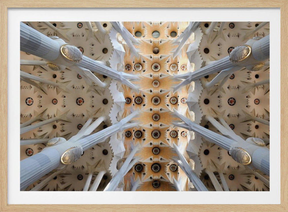 A symmetrical photograph looking directly up at the ornate, geometric ceiling of the Sagrada Familia. White, tree-like columns branch out to support the intricate vaulted ceiling, which is detailed with warm orange and gold starburst patterns. Decor