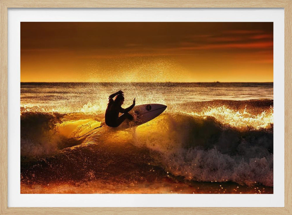 A silhouetted surfer carves a turn on a sun-kissed wave during a vibrant orange sunset, with golden light reflecting off the water and sea spray. Wall Art