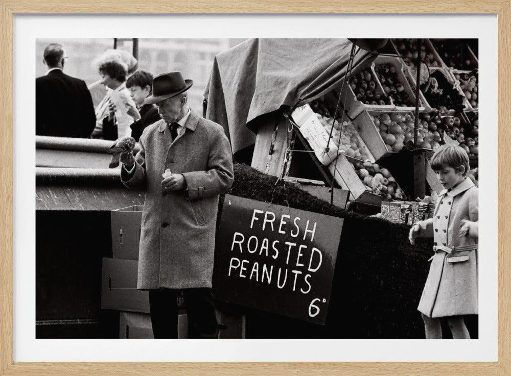 A vintage black and white photograph of an elderly man in a fedora and overcoat feeding a pigeon from his hand at an outdoor market. A sign for 'FRESH ROASTED PEANUTS' is visible next to him, and a young boy in a coat watches nearby. Wall Art