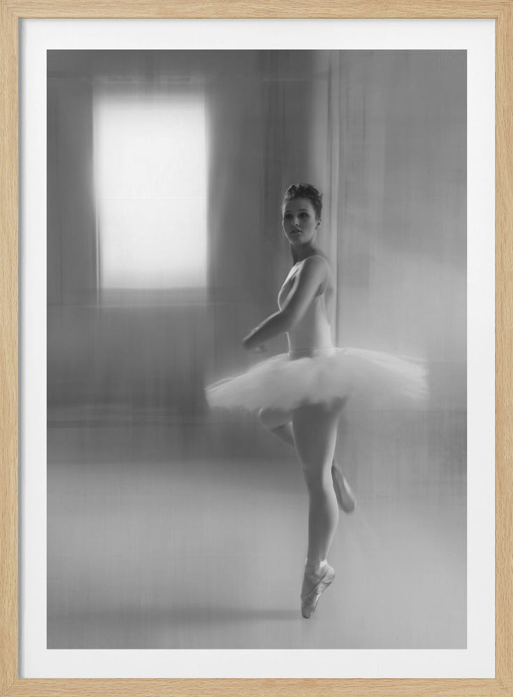 A black and white artistic photograph of a ballerina in a white leotard and tutu, mid-pose on pointe. The image has a motion blur effect, creating a dreamy and ethereal atmosphere as she glances back at the camera. Decor