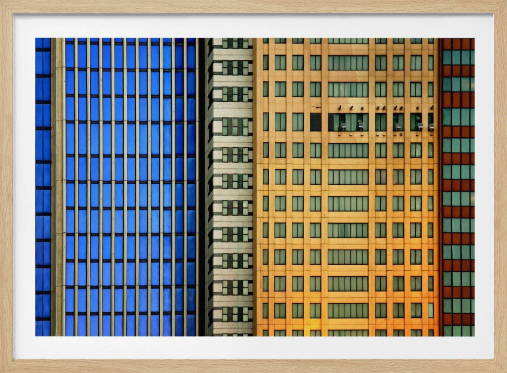 An abstract architectural photograph showing the colorful gridded facades of three adjacent skyscrapers, featuring a blue-windowed building, a white building, and a yellow building, all contained within a silver frame. Wall Art