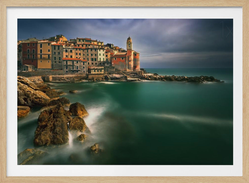 A dramatic long-exposure photograph of a historic coastal village in Italy, possibly Cinque Terre, with colorful buildings and a church perched on rocky cliffs. The sea is a smooth, ethereal teal green, and the sky is filled with dark, stormy clouds. Poster