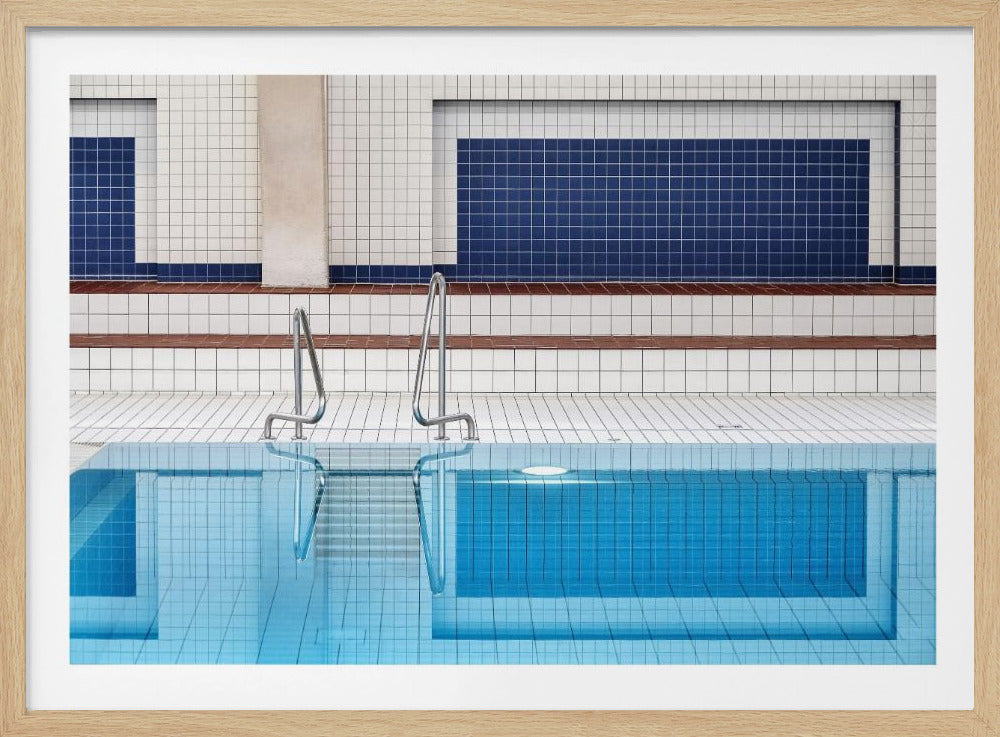 A framed, symmetrical photograph of a minimalist indoor swimming pool with blue and white tiles, stainless steel ladders, and a calm, reflective water surface. Poster