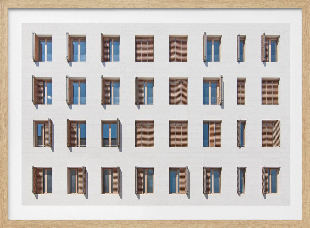 A symmetrical architectural photo of a modern white building facade featuring a grid of twenty-eight windows with wooden louvered shutters, some open and some closed, creating a varied pattern, all within a brushed silver frame. Decor