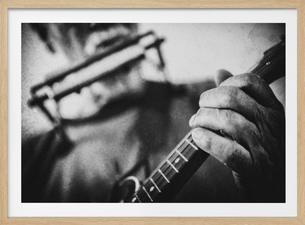 A grainy, black and white close-up photograph of a musician's hand gripping the neck of a stringed instrument. The focus is on the hand and the frets, with the musician's body and face softly blurred in the background. The image is enclosed in a silver frame. Wall Art