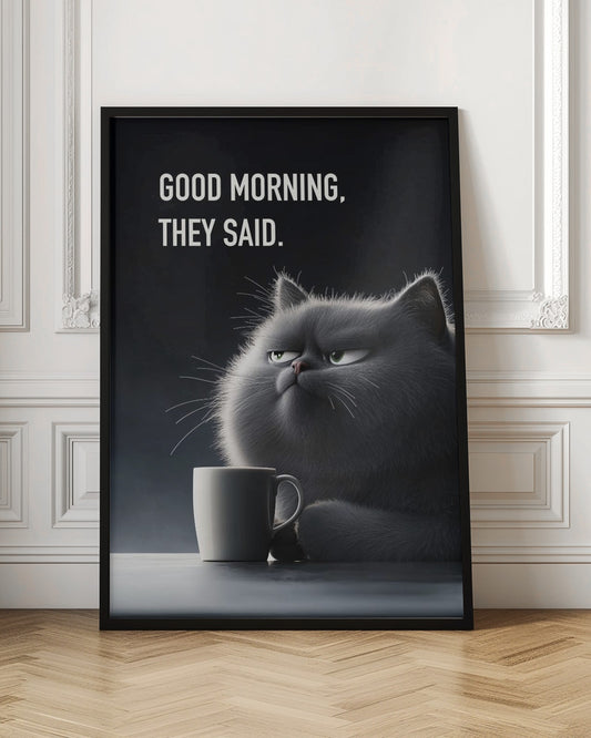 A framed poster featuring a very fluffy, gray, cartoon-style cat with a grumpy expression, looking sideways. The cat is sitting at a table with a white coffee mug. Above the cat, white text on a dark gray background reads, 'GOOD MORNING, THEY SAID.' Artwork