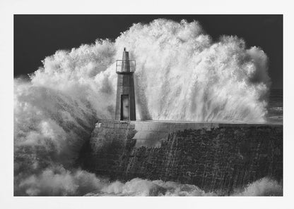 A dramatic black and white photograph of a massive wave crashing against a stone pier and a small lighthouse. The white foam of the wave towers over the structure, creating a powerful and dynamic scene against a dark sky, all enclosed in a silver frame. Poster