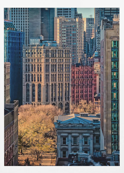 A high-angle view of a dense city skyline featuring a mix of old and new architectural styles. Golden light illuminates the autumn foliage of a park and the facades of several buildings, creating a warm contrast with the cool blue tones of the skyscrapers in the background. Decor