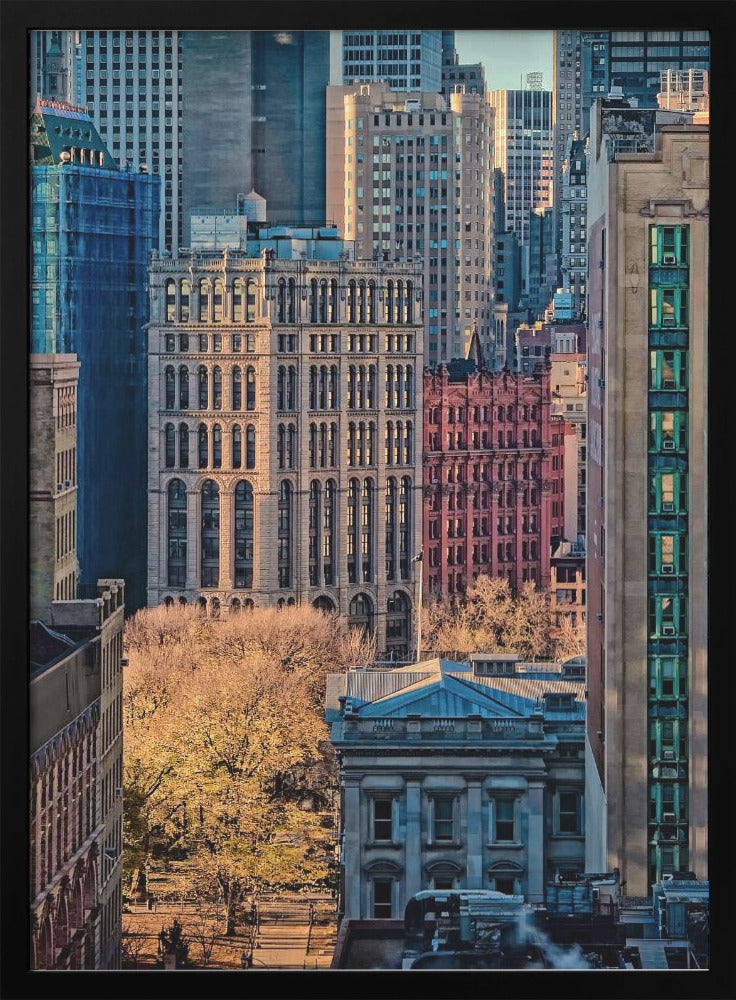 A high-angle view of a dense city skyline featuring a mix of old and new architectural styles. Golden light illuminates the autumn foliage of a park and the facades of several buildings, creating a warm contrast with the cool blue tones of the skyscrapers in the background. Decor