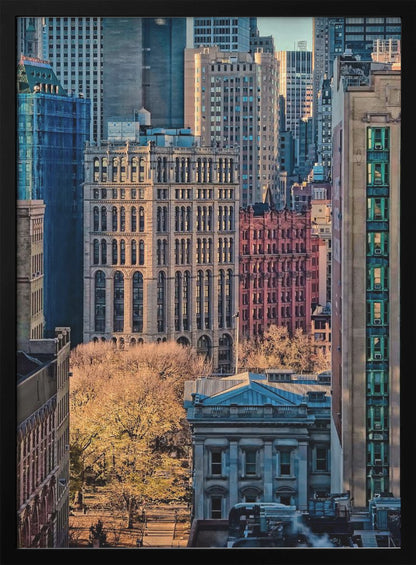 A high-angle view of a dense city skyline featuring a mix of old and new architectural styles. Golden light illuminates the autumn foliage of a park and the facades of several buildings, creating a warm contrast with the cool blue tones of the skyscrapers in the background. Decor