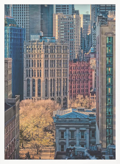 A high-angle view of a dense city skyline featuring a mix of old and new architectural styles. Golden light illuminates the autumn foliage of a park and the facades of several buildings, creating a warm contrast with the cool blue tones of the skyscrapers in the background. Decor