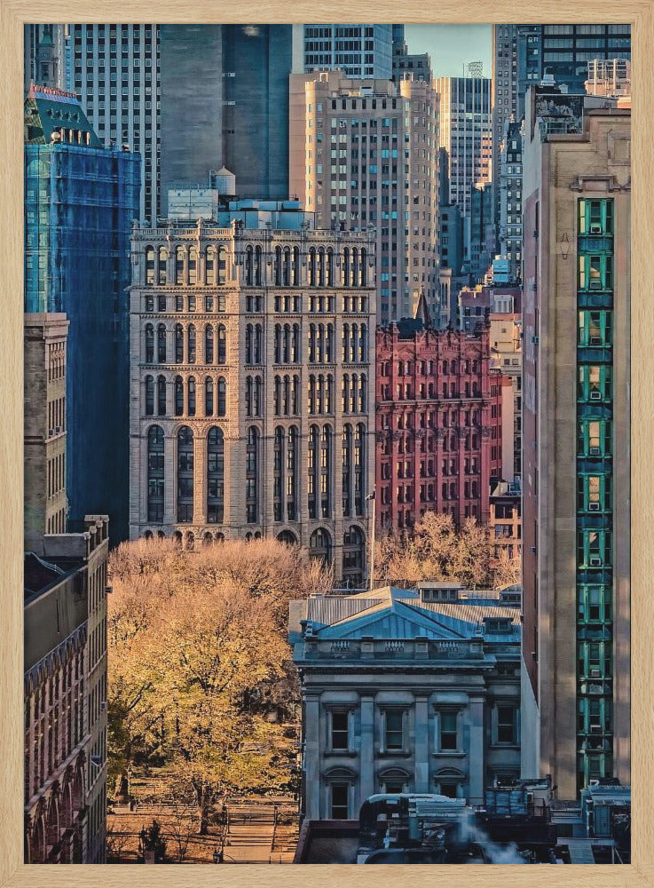 A high-angle view of a dense city skyline featuring a mix of old and new architectural styles. Golden light illuminates the autumn foliage of a park and the facades of several buildings, creating a warm contrast with the cool blue tones of the skyscrapers in the background. Decor