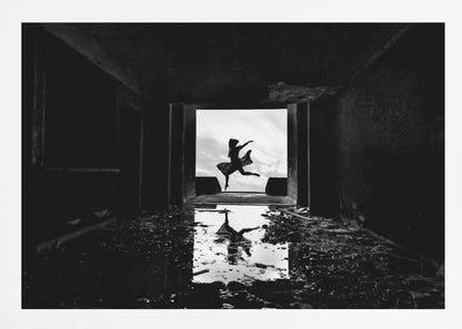 A dramatic black and white photo of a silhouetted dancer leaping in a bright doorway, viewed from inside a dark, derelict building. The dancer's reflection is captured in a puddle on the rubble-strewn floor. Poster