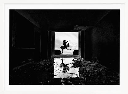 A dramatic black and white photo of a silhouetted dancer leaping in a bright doorway, viewed from inside a dark, derelict building. The dancer's reflection is captured in a puddle on the rubble-strewn floor. Poster