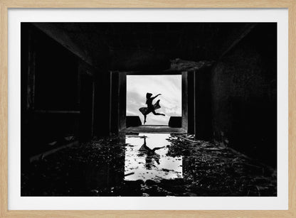 A dramatic black and white photo of a silhouetted dancer leaping in a bright doorway, viewed from inside a dark, derelict building. The dancer's reflection is captured in a puddle on the rubble-strewn floor. Poster