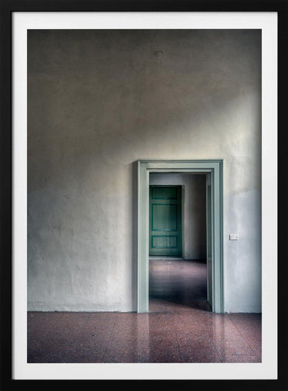 A minimalist photograph of a room with grey, textured walls and a reddish-brown floor, focusing on an open, light green doorway that reveals another room with a closed, darker green door, creating a sense of depth and perspective. Wall Art