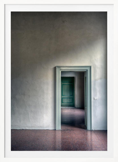 A minimalist photograph of a room with grey, textured walls and a reddish-brown floor, focusing on an open, light green doorway that reveals another room with a closed, darker green door, creating a sense of depth and perspective. Wall Art
