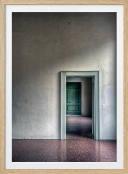 A minimalist photograph of a room with grey, textured walls and a reddish-brown floor, focusing on an open, light green doorway that reveals another room with a closed, darker green door, creating a sense of depth and perspective. Wall Art