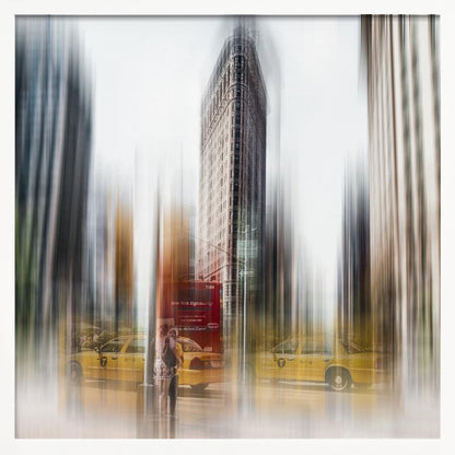 An artistic photograph of New York City's Flatiron Building in a light wood frame. The image has a strong vertical motion blur effect, creating streaks of yellow from taxi cabs and gray from the surrounding architecture, capturing the bustling energy of the city. Poster