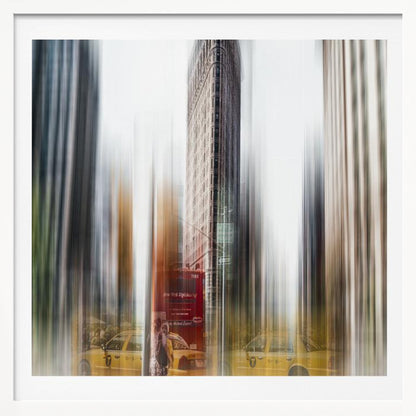 An artistic photograph of New York City's Flatiron Building in a light wood frame. The image has a strong vertical motion blur effect, creating streaks of yellow from taxi cabs and gray from the surrounding architecture, capturing the bustling energy of the city. Poster