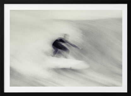 An artistic black and white photograph using motion blur to capture a surfer in a dynamic, fluid pose on a wave. The slow shutter speed creates a sense of speed and abstract movement, with the surfer's dark wetsuit contrasting against the white, streaked water. The image is presented in a silver frame. Decor