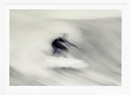 An artistic black and white photograph using motion blur to capture a surfer in a dynamic, fluid pose on a wave. The slow shutter speed creates a sense of speed and abstract movement, with the surfer's dark wetsuit contrasting against the white, streaked water. The image is presented in a silver frame. Decor