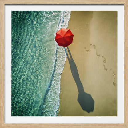 An aerial photograph of a serene beach scene, featuring a vibrant red umbrella on the golden sand next to the clear turquoise ocean. Gentle white waves lap the shore, and a long shadow from the umbrella stretches across the sand, where a trail of footprints leads away. Poster