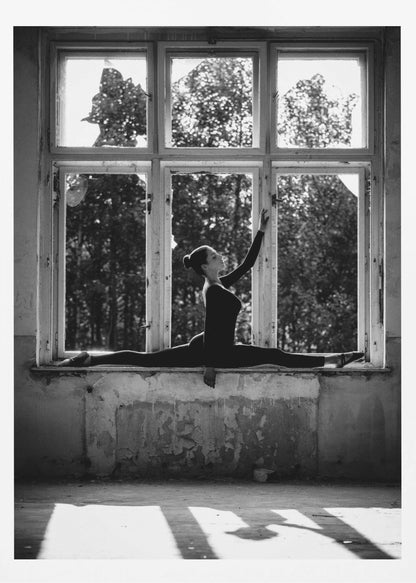 A black and white photograph of a graceful female dancer holding a perfect split on a large, dilapidated windowsill. She is silhouetted against the bright light from the broken window panes, with her arm elegantly raised. The setting is an abandoned room with peeling paint, creating a stark contrast between the dancer's elegance and the decaying environment. Wall Art