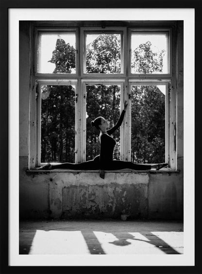 A black and white photograph of a graceful female dancer holding a perfect split on a large, dilapidated windowsill. She is silhouetted against the bright light from the broken window panes, with her arm elegantly raised. The setting is an abandoned room with peeling paint, creating a stark contrast between the dancer's elegance and the decaying environment. Wall Art