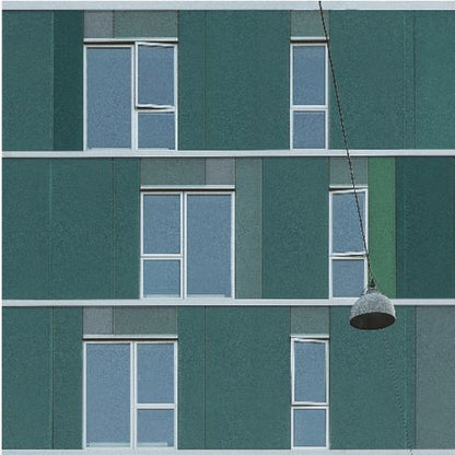 A framed photograph of a modern, dark green building facade with a grid of windows across three levels. A single industrial-style pendant lamp hangs in front of the building on the right side, interrupting the symmetrical pattern. The entire scene is enclosed by a light wood frame. Decor