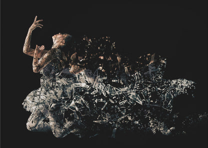 A conceptual piece of artwork depicting a woman in a dynamic pose against a solid black background. Her form appears to be shattering and dissolving into a swirling cloud of broken glass shards, creating a powerful and dramatic effect. The piece is presented within a simple silver frame. Print