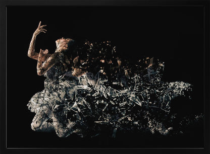 A conceptual piece of artwork depicting a woman in a dynamic pose against a solid black background. Her form appears to be shattering and dissolving into a swirling cloud of broken glass shards, creating a powerful and dramatic effect. The piece is presented within a simple silver frame. Print