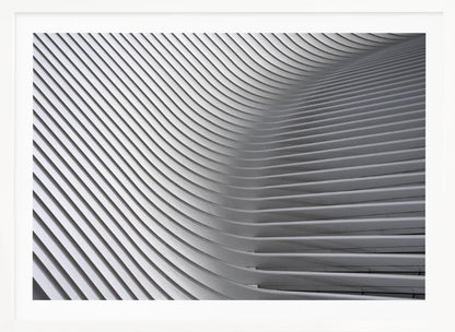 A framed, close-up, abstract photograph of a modern architectural structure. Parallel white ribs curve and undulate across the frame, creating a sense of movement and rhythm through the interplay of light and shadow. Artwork