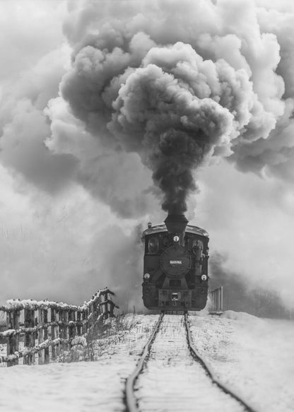 A dramatic black and white photograph of a vintage steam train on tracks in a snowy landscape, viewed from a low angle. A massive, powerful plume of dark smoke billows from the smokestack, filling the sky. Decor