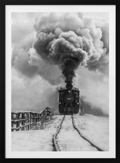 A dramatic black and white photograph of a vintage steam train on tracks in a snowy landscape, viewed from a low angle. A massive, powerful plume of dark smoke billows from the smokestack, filling the sky. Decor