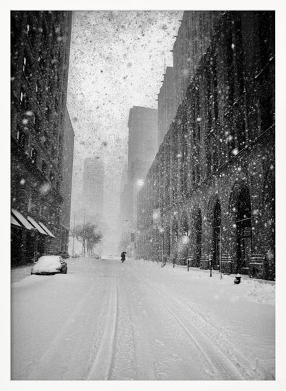 A grainy, black and white photograph captures a deserted city street during a heavy snowstorm. Tall buildings line the street, which is covered in a thick blanket of snow. A single car on the left is almost completely buried, and in the distance, a lone figure walks with an umbrella down the center of the empty road. Poster