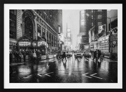 A moody black and white photograph of a snowy day in New York City's Times Square. The wet streets reflect the bright lights of the surrounding buildings and billboards as pedestrians cross the street and cars wait in traffic. Artwork