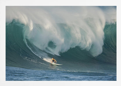 A lone surfer in a yellow shirt rides down the face of an enormous, powerful ocean wave as it crests into white foam, viewed within a silver picture frame. Wall Art