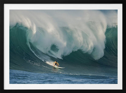 A lone surfer in a yellow shirt rides down the face of an enormous, powerful ocean wave as it crests into white foam, viewed within a silver picture frame. Wall Art