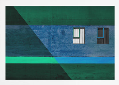 A framed abstract architectural photograph featuring a color-blocked facade. A central horizontal band of textured blue wall contains two small, distinct windows. This is flanked by upper and lower sections of dark green. A large, dark diagonal shape overlays the left side of the composition, creating sharp geometric lines. Decor