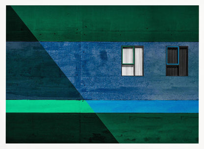 A framed abstract architectural photograph featuring a color-blocked facade. A central horizontal band of textured blue wall contains two small, distinct windows. This is flanked by upper and lower sections of dark green. A large, dark diagonal shape overlays the left side of the composition, creating sharp geometric lines. Decor