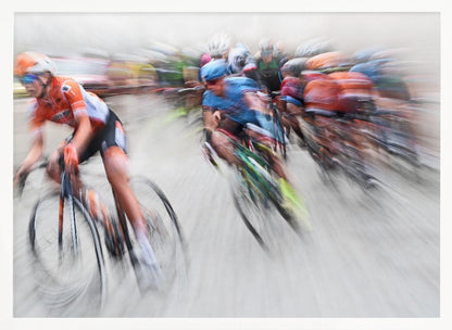 An action photograph of a professional cycling race captured with a prominent motion blur effect that conveys a strong sense of speed. A cyclist in an orange and black uniform is in the foreground, leaning into a turn, while a group of other riders in blue and multi-colored jerseys follows closely behind, their forms streaked and blurred. The entire scene is encased in a brushed silver frame. Poster