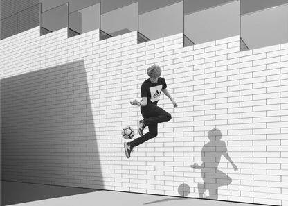 A framed, black and white photograph of a young person in mid-air, skillfully juggling a soccer ball with their foot against a clean, white brick wall. The person's shadow is cast sharply on the wall, mirroring the action, under a modern building with angled windows. Wall Art