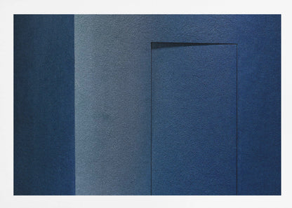 An abstract geometric artwork featuring textured panels in various shades of deep and dusty blue. The composition is divided into vertical sections, with a central rectangular shape that appears slightly recessed, creating a strong shadow line at its top edge. The piece is enclosed in a simple, brushed silver frame. Wall Art