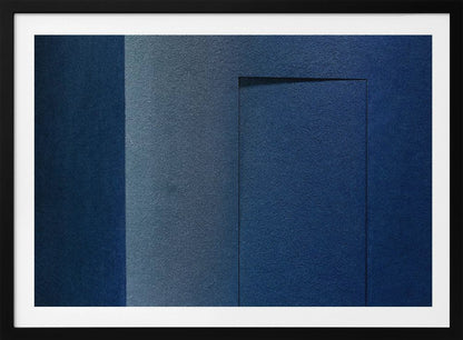 An abstract geometric artwork featuring textured panels in various shades of deep and dusty blue. The composition is divided into vertical sections, with a central rectangular shape that appears slightly recessed, creating a strong shadow line at its top edge. The piece is enclosed in a simple, brushed silver frame. Wall Art