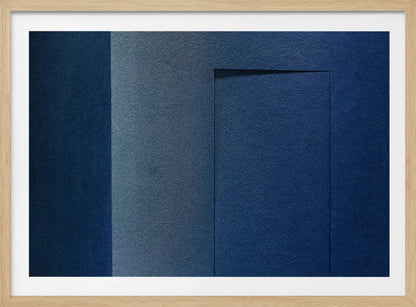 An abstract geometric artwork featuring textured panels in various shades of deep and dusty blue. The composition is divided into vertical sections, with a central rectangular shape that appears slightly recessed, creating a strong shadow line at its top edge. The piece is enclosed in a simple, brushed silver frame. Wall Art