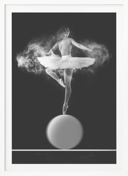 A dramatic black and white photograph of a ballerina balancing on one pointe shoe on top of a large sphere. She wears a white tutu and is surrounded by a cloud of white powder, capturing a moment of explosive, graceful movement against a solid black background. Wall Art