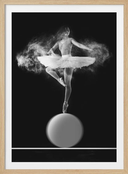 A dramatic black and white photograph of a ballerina balancing on one pointe shoe on top of a large sphere. She wears a white tutu and is surrounded by a cloud of white powder, capturing a moment of explosive, graceful movement against a solid black background. Wall Art